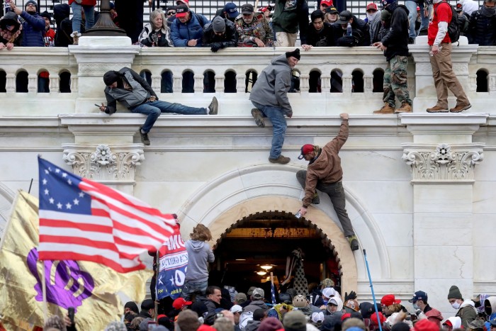 A crowd of supporters of US President Donald Trump fight with law enforcement personnel at a door they broke down as they stormed the US Capitol in Washington, on January 6, 2021.