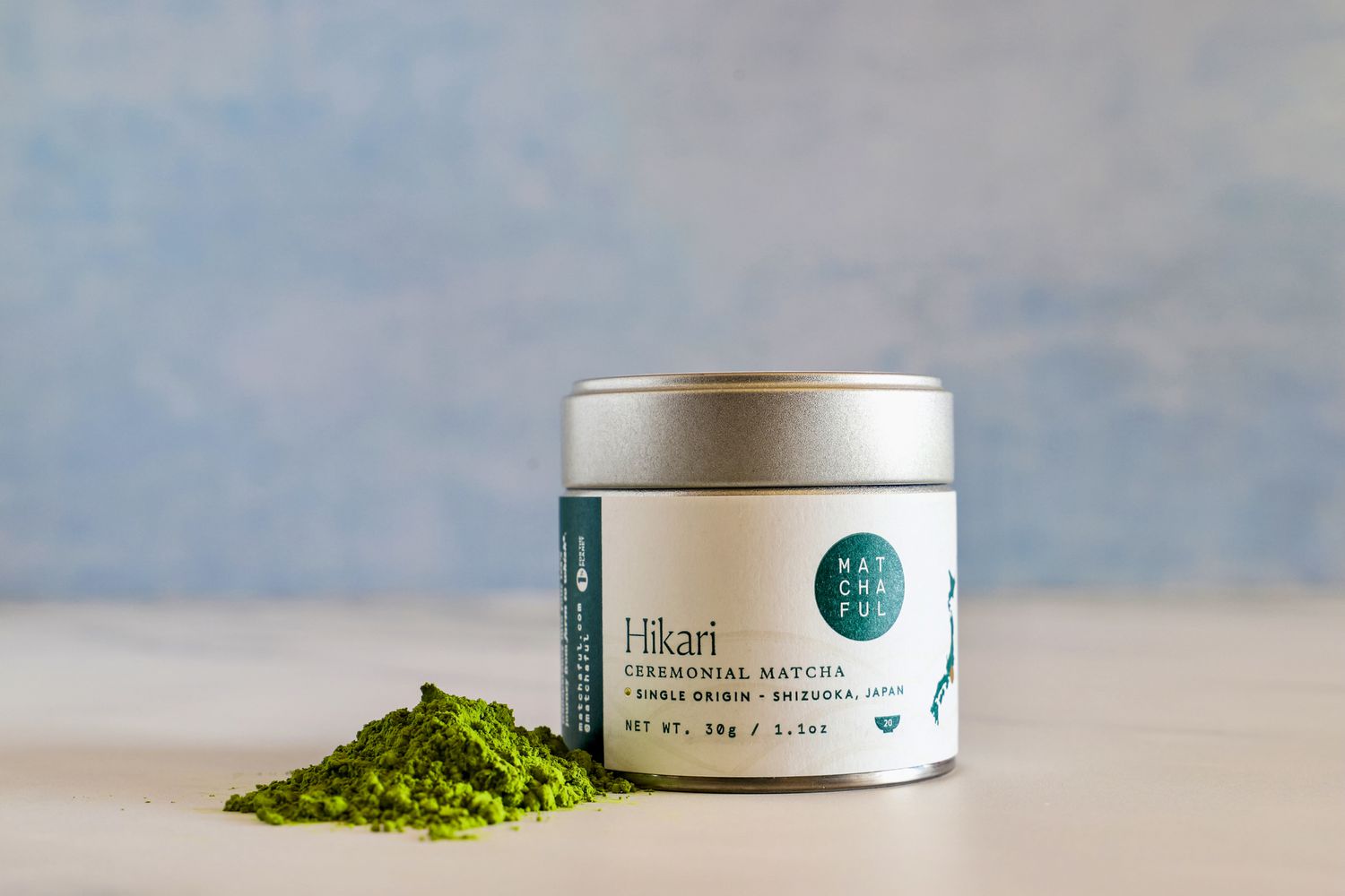 A container of Matchaful Hikari Single Origin Matcha next to a pile of the powder