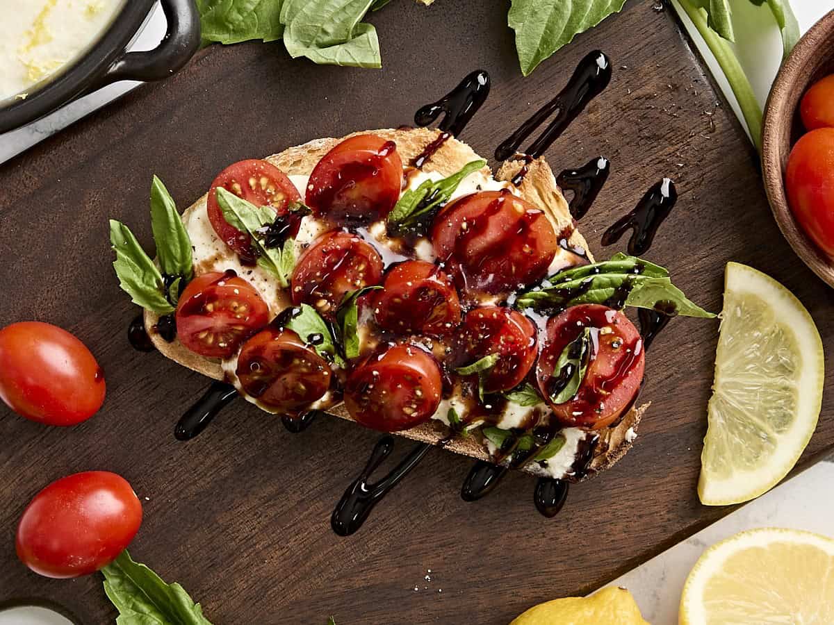 Overhead view of ricotta toast with blistered tomatoes, basil, and balsamic reduction.