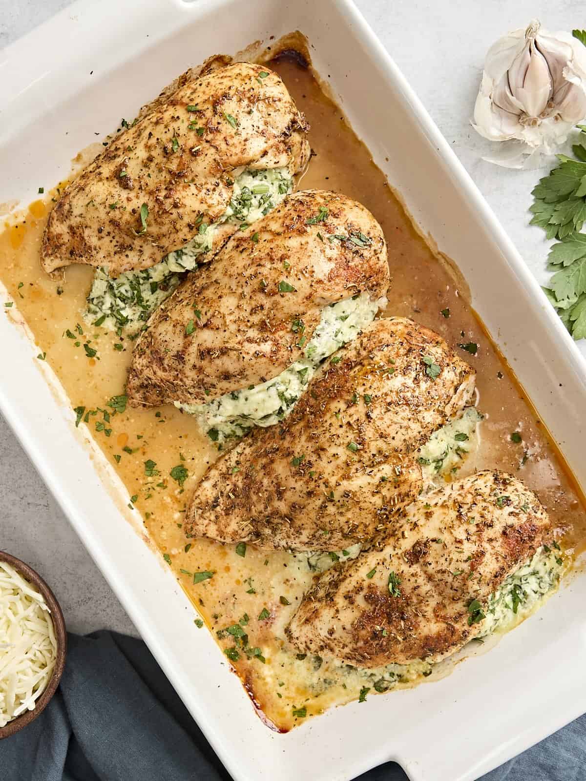 Overhead view of spinach stuffed chicken breasts in a baking dish.