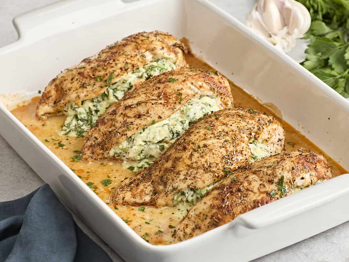 Side view of spinach stuffed chicken breasts in a baking dish.