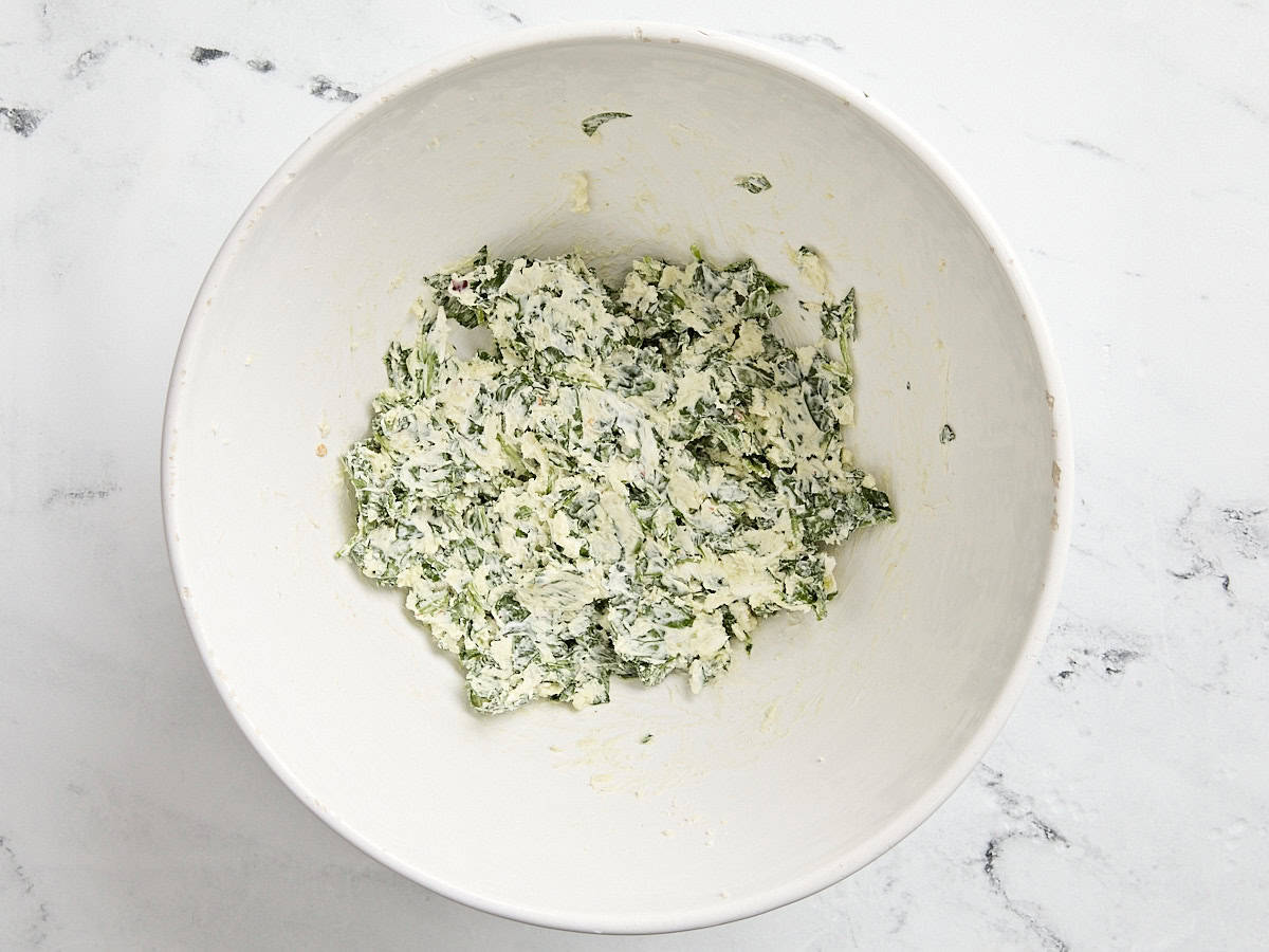 The filling for stuffed spinach chicken breast in a mixing bowl.