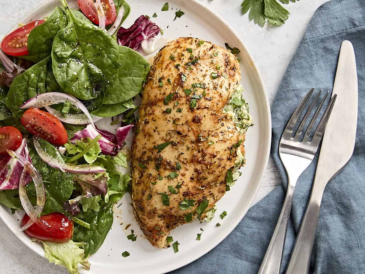 Overhead view of a spinach stuffed chicken breast on a plate with a salad.