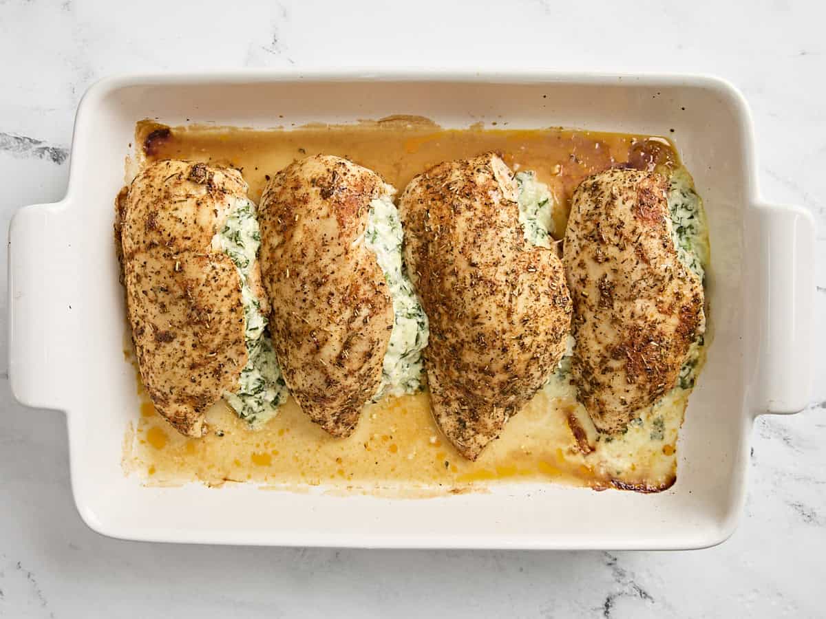 Finished spinach stuffed chicken breasts in a baking dish.