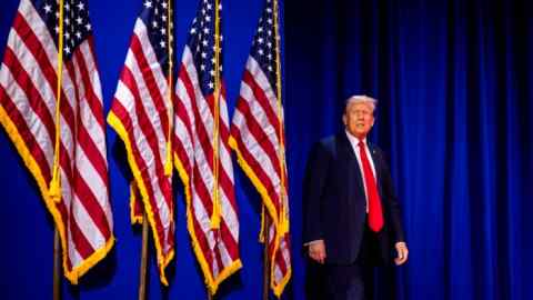 Donald Trump stands on stage next to American flags